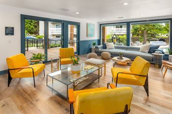 A living room with yellow chairs and a glass table.